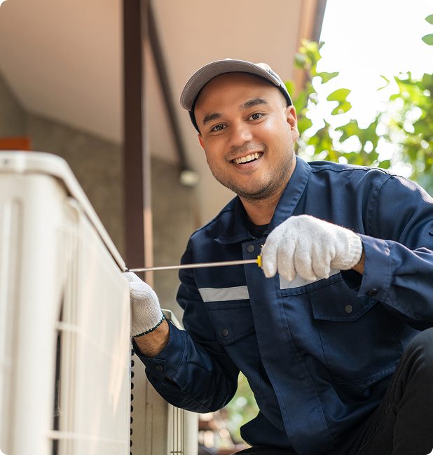Smiling technician repairing an outdoor unit.